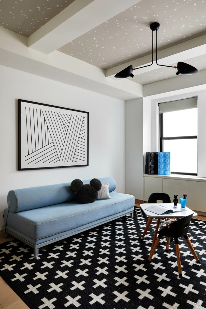 小孩游戏室配有Diskune入睡沙发,并配有Potterybank Mickey枕头和CB2白枕头天花板灯Serge Moille和恒星墙纸ColeSonsLalo打表和椅子坐在Crate和Barre