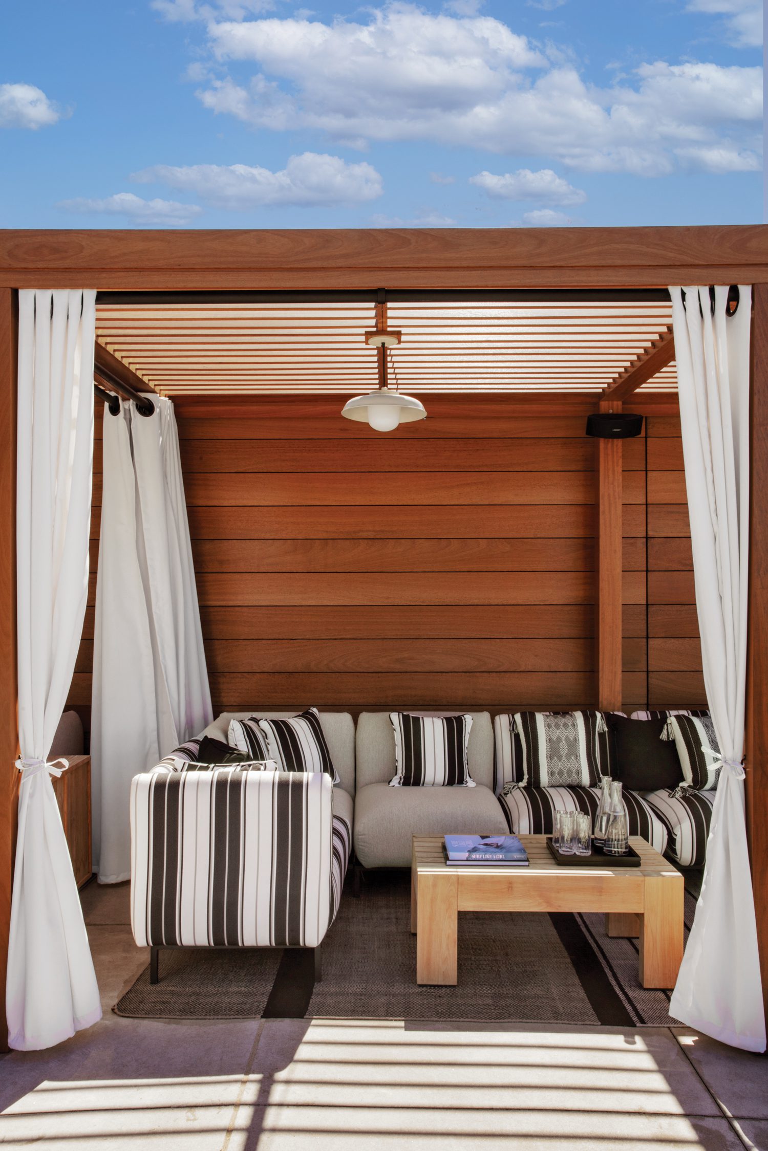 池边卡巴纳带区沙发、木板墙和白窗帘树冠