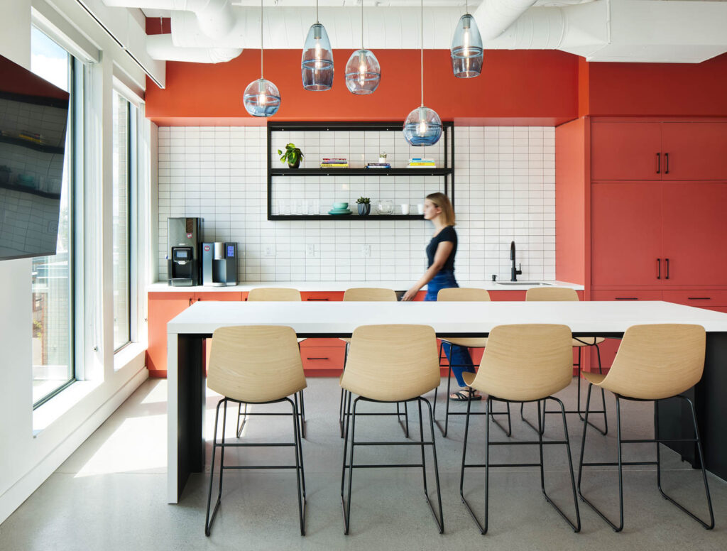 一个女人走过厨房区,带橙色柜子和白表