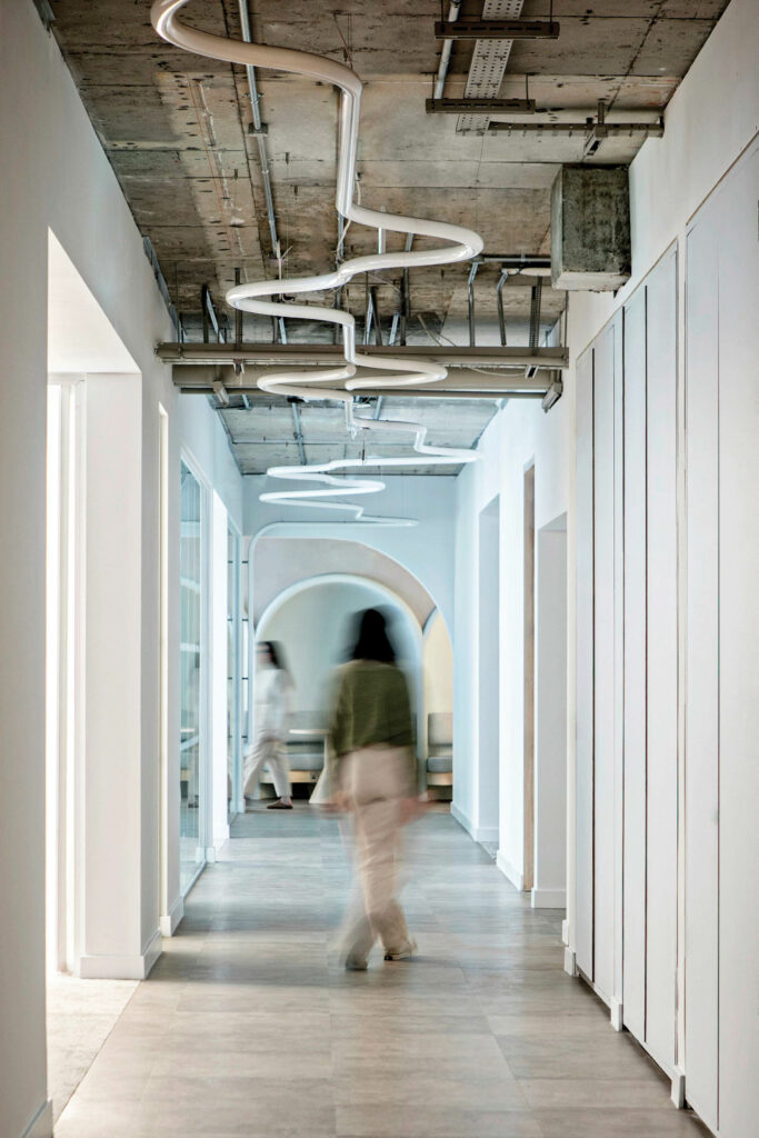 一个女人走工业走廊 上方有裸天花板和白LED光电