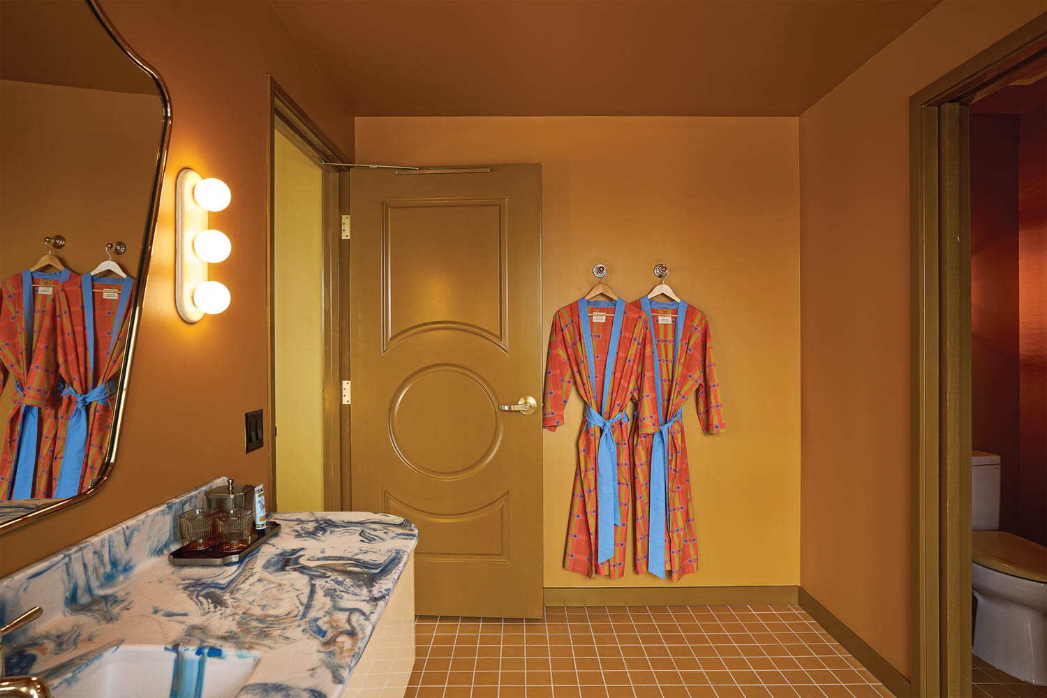 长袍挂在黄色卫生间墙上并配有黄瓦地板