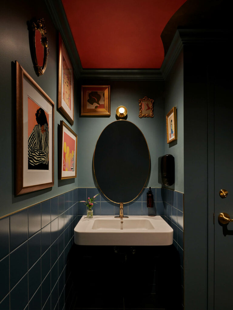 深绿卫生间配有白水槽和画廊墙