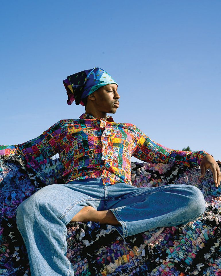 穿多色按键衬衣和牛仔裤的人坐在上轮地毯上