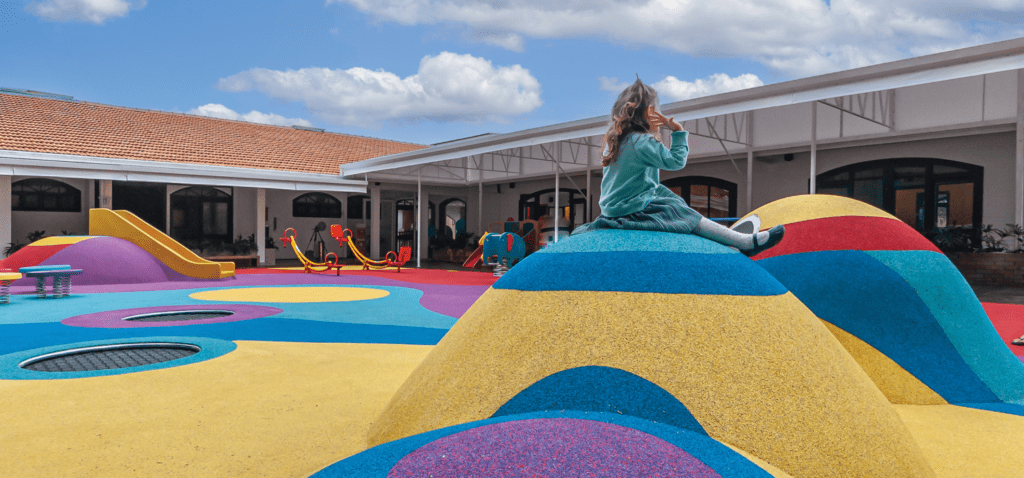 儿童坐在学校游乐场多色丘上