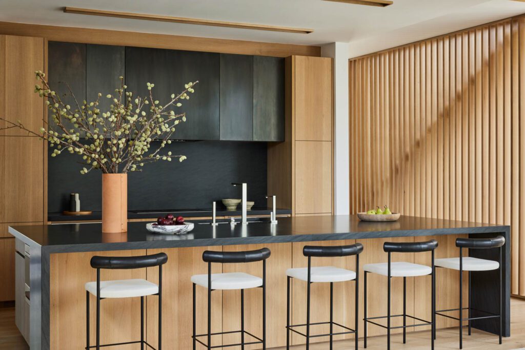 厨房用深花岗对数板隔开进口,用板状木墙,并起悬浮金属楼梯的楼梯墙作用。